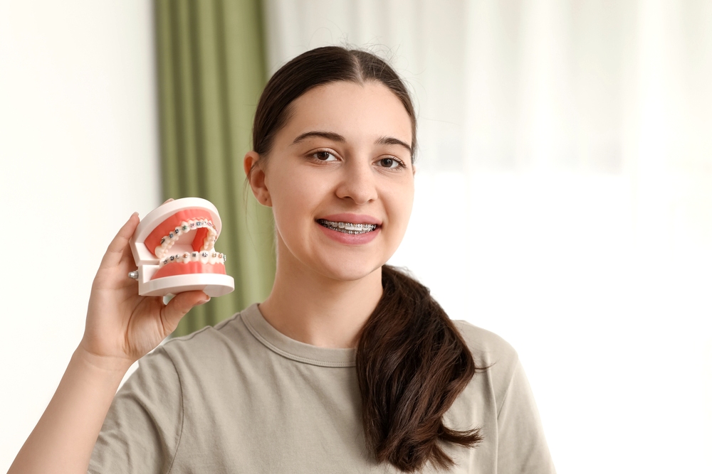 beautiful young woman metal braces holding jaw model while explaining braces cost in little rock, AR