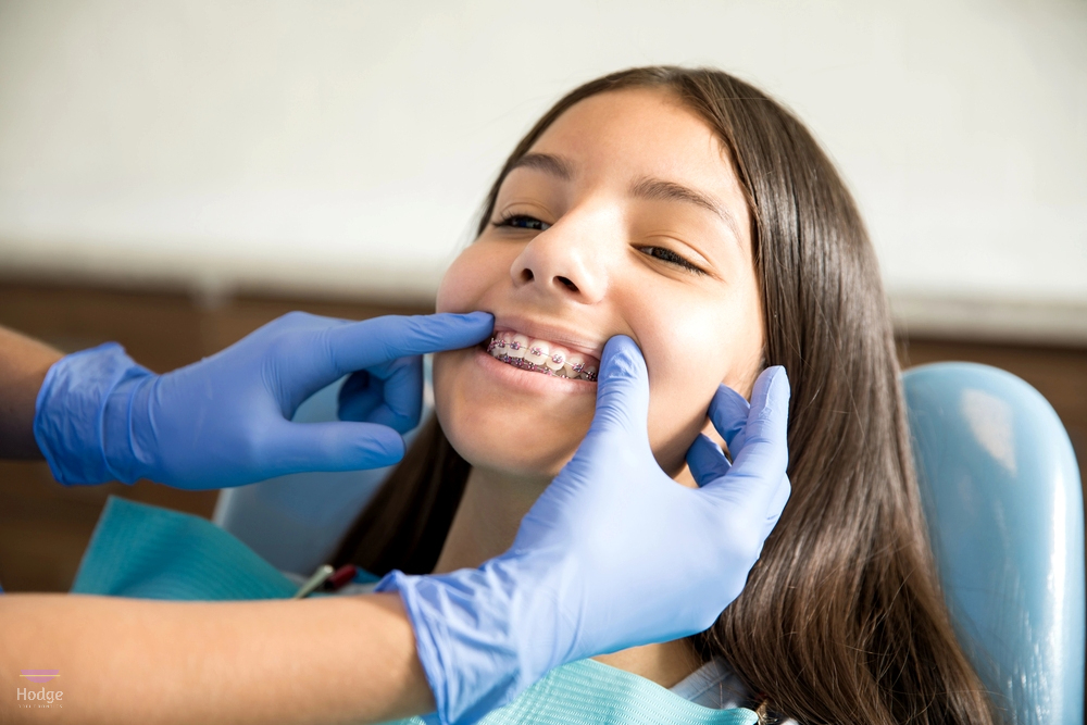 teenage girl metal braces being examined dentist wearing gloves clinic illustrating Braces cost in little rock, AR