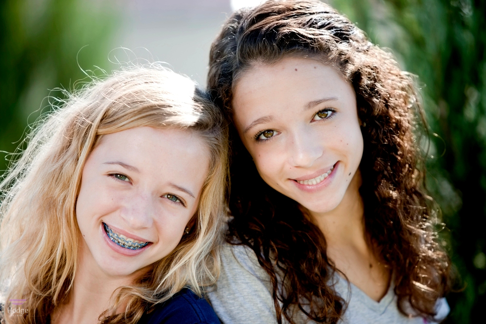 two smiling caucasian metal braces teenage girls in the park after understanding braces cost in little rock, AR
