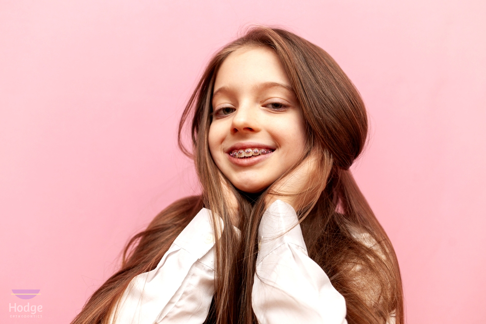 Confident young woman posing against a pink background, smiling naturally after orthodontic braces for overbite in little rock, ar treatment.