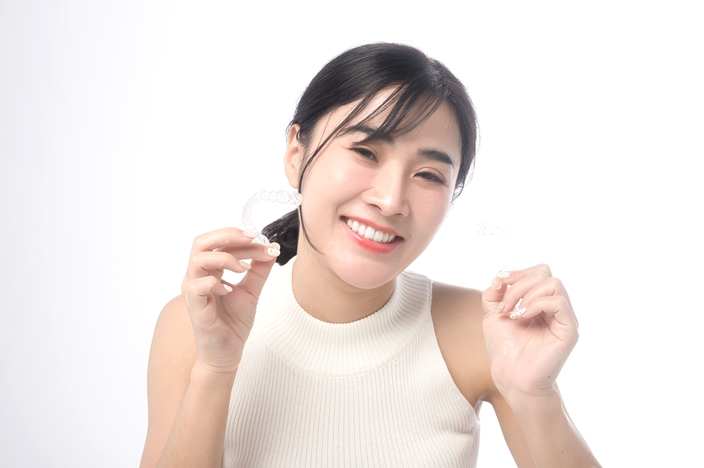 young smiling woman holding invisalign clear aligners white background studio dental 1 - Can Invisalign Fix Overbite in Little Rock, AR.